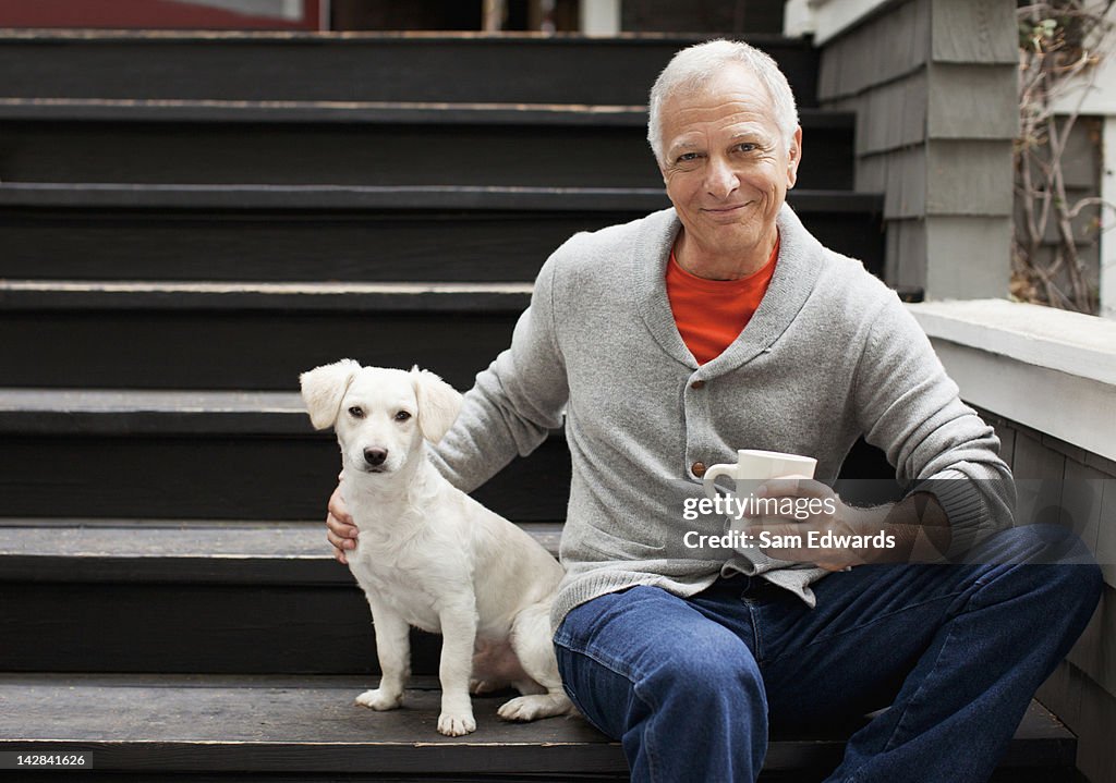 Older man petting puppy on steps outdoors