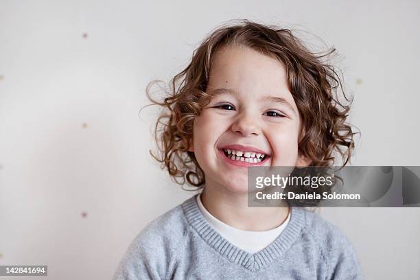 portrait of smiling boy with curly brown hair - childs pose fotografías e imágenes de stock