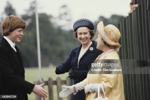 Queen Elizabeth II and the Queen Mother shake hands with Viscount Althorp, later the 9th Earl Spencer, during the Eton Boys' Tea Party at Windsor,...