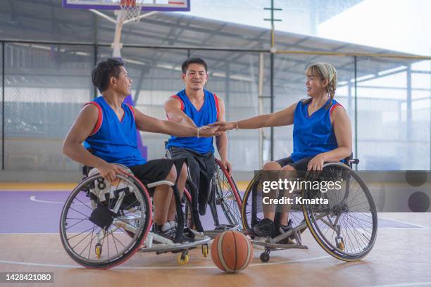 group of wheelchair basketball players putting hands together. - adaptive athlete - fotografias e filmes do acervo