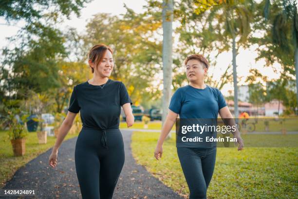 behinderte asiatische chinesin mit deformiertem armamputierten, die mit einer freundin im öffentlichen park täglich läuft - of deformed people stock-fotos und bilder