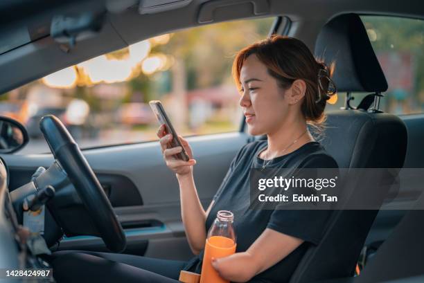chinese woman with disability deformed arm amputee texting message drinking water before starting her journey sitting on driver seat at parking lot - of deformed people stock pictures, royalty-free photos & images