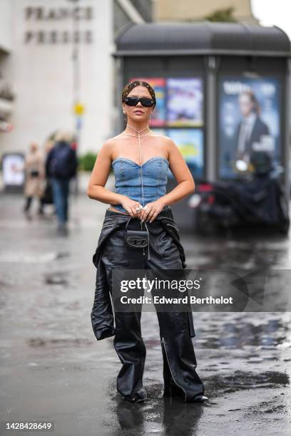 Guest wears rhinestones hair jewels, black sunglasses from Chanel, silver earrings, silver chain necklaces, a blue denim shoulder-off corset, a black...