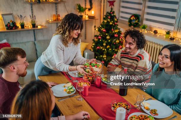 woman serving meal for friends - vegan christmas dinner stock pictures, royalty-free photos & images