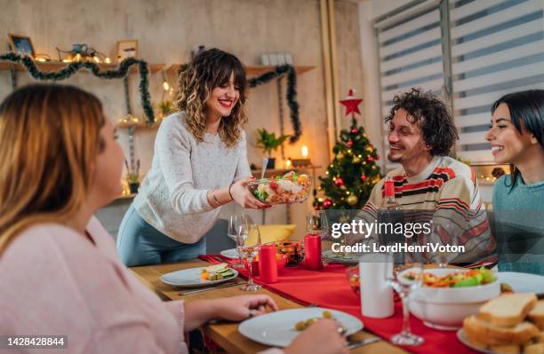woman serving meal for friends - vegan christmas dinner stock pictures, royalty-free photos & images