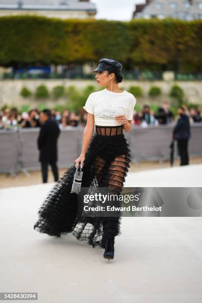 Guest wears a black shiny leather with embroidered mesh yoke cap, a white with black inscriptions print pattern cropped t-shirt, silver and diamonds...