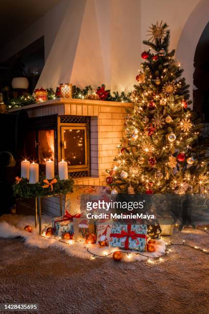 weihnachtsbaum mit geschenken eingewickelt im gemütlichen wohnzimmer mit kamin an heiligabend - adventkranz stock-fotos und bilder