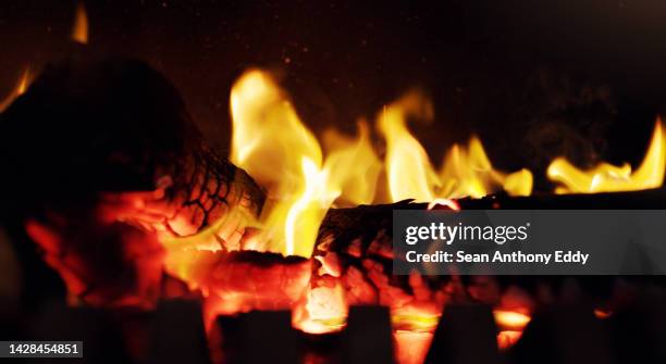 feuer, flamme und holz brennen in einem kamin für einen grill oder wärme im winter. flammen, funken und licht, glut leuchten im dunkeln. gemütlich, warm und gemütlich in einer kalten nacht, ein lagerfeuer zum kochen oder grillen. - wood burning stove stock-fotos und bilder