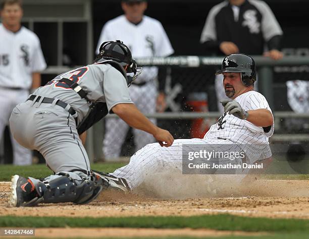 Pail Konerko of the Chicago White Sox beats the tag by Alex Avila of the Detroit Tigers to score a run in the 6th inning during the opening day game...