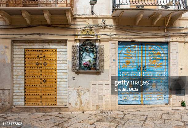 Colorful painted roller shutters on shop display window, Kasbah Mazara del Vallo, Sicily, Italy.