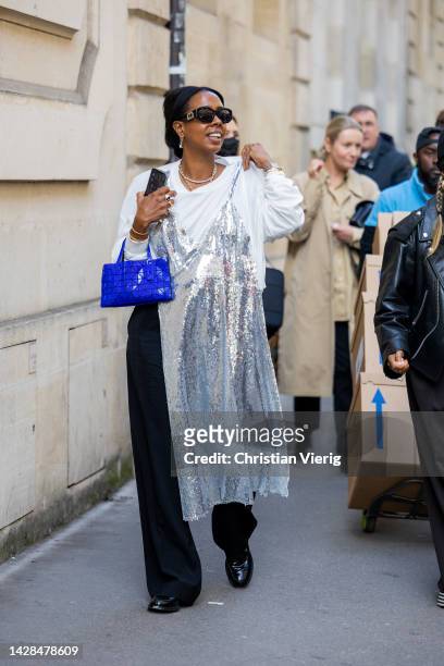 Guest wears white shirt, silver dress, blue bag, black pants outside The Row during Paris Fashion Week - Womenswear Spring/Summer 2023 : Day Three on...