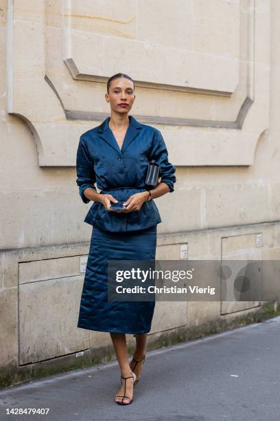 Guest wears blue button shirt, tube skirt, heeled sandals, black bag outside The Row during Paris Fashion Week - Womenswear Spring/Summer 2023 : Day...