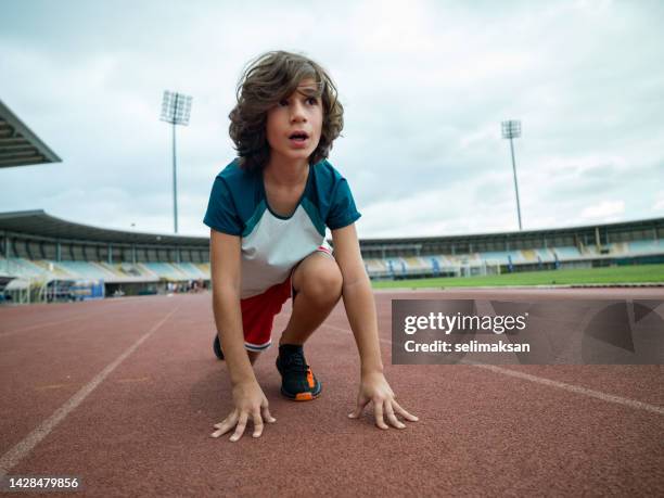 photo of boy ready to run in stadium - boy running track stock pictures, royalty-free photos & images