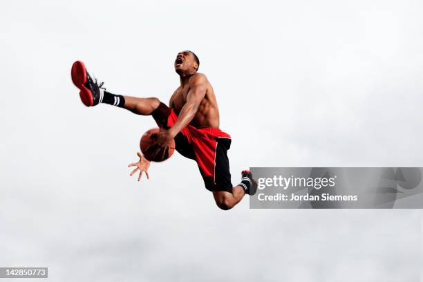 man slam dunking a basketball. - slam dunk stock pictures, royalty-free photos & images