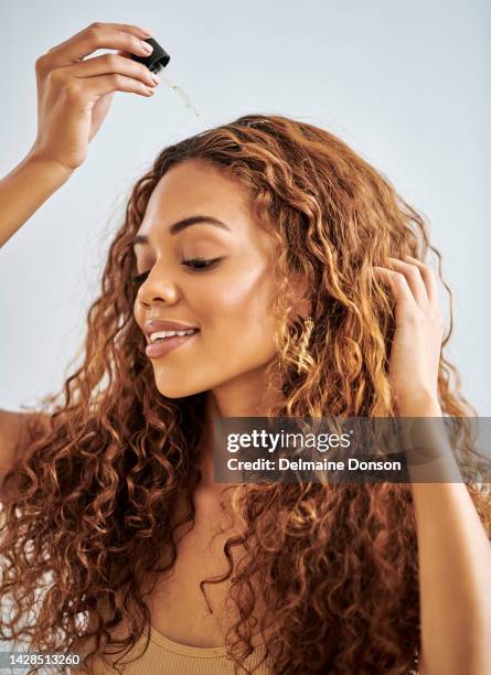 woman, curly and hair care argan oil for healthy growth, frizz management and dandruff treatment. smile, happy and beauty model with organic dropper serum product, makeup cosmetics or skincare health - applying oil stock pictures, royalty-free photos & images