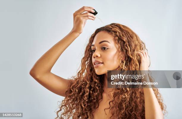 ヘアオイル、ヘアトリートメント、自然な、長くて巻き毛の女性へのヘアケア。健康なカール、強いロックと成長のための血清、髪の修復とヘア製品を使用して若い女の子の肖像画 - hair products ストックフォトと画像
