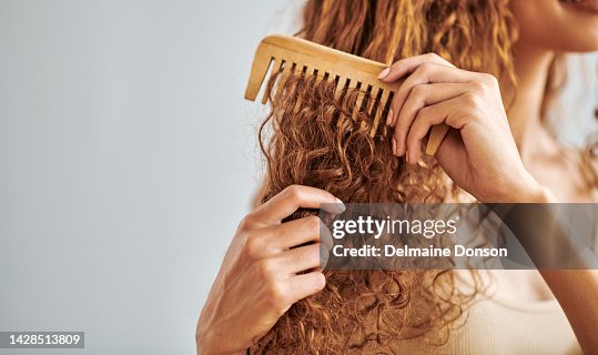 Limpieza, belleza y cuidado del cabello por parte de la mujer cepilla y peina su cabello natural y rizado en el baño de su casa. Higiene, encrespamiento y control de daños con manos femeninas peinan el cabello natural en la rutina matutina Limpieza, belleza y cuidado del cabello por parte de la mujer cepilla y peina su cabello natural y rizado en el baño de su casa. Higiene, encrespamiento y control de daños con manos femeninas peinan el cabello natural en la rutina matutina