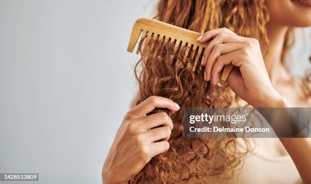 nettoyage, beauté et soins capillaires par la femme brosser et coiffer ses cheveux naturels et bouclés dans la salle de bain de sa maison. hygiène, frisottis et contrôle des dommages avec des mains féminines peignent les cheveux naturels dans la routi - cheveux frisés photos et images de collection