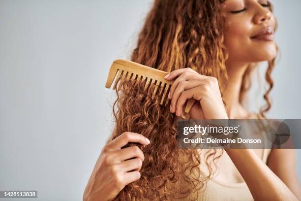 cuidado del cabello, belleza y mujer cepillando su cabello rizado con un peine de madera durante su rutina de cuidado personal. hermosa, joven e hispana peinando sus cerraduras naturales limpias en un estudio con espacio de copia. - hair products fotografías e imágenes de stock