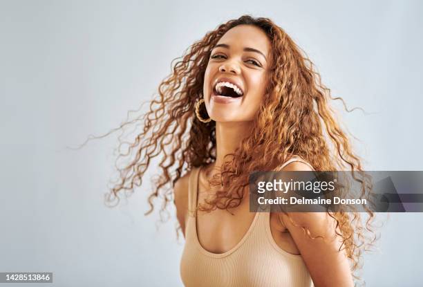 happy woman, curly hair and natural beauty while laughing, happy and joy over a studio background. playful, good news and attractive female model feeling positive, cheerful and excited about an offer - dry hair stock pictures, royalty-free photos & images