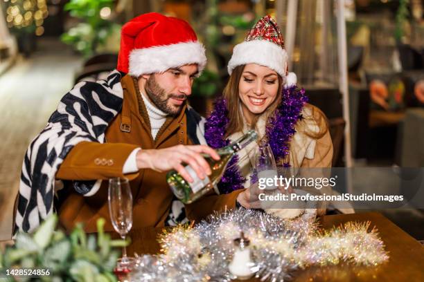 cheerful young couple is sitting in a cafe and toasting with a wine. - coat imagens e fotografias de stock
