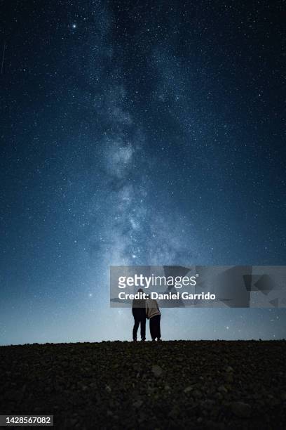 embraced romantic couple enjoying a starry night, contemplating the milky way, couples and stars - star field fotografías e imágenes de stock