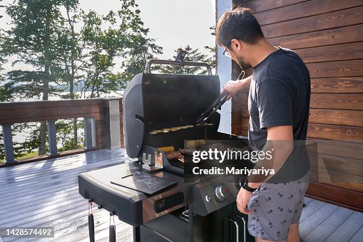 A man cooks grilled meat on a picturesque terrace in sunny weather. A man cooks grilled meat on a picturesque terrace in sunny weather.
