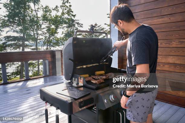 a man cooks grilled meat on a picturesque terrace in sunny weather. - gas appliances stock-fotos und bilder