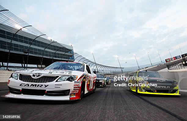 Denny Hamlin, driver of the SportClips Toyota, and Paul Menard, driver of the Menards/Rheem Chevrolet, take a pace lap before the start of the NASCAR...