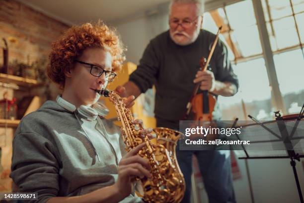 happy senior man and grandson having fun while playing saxophone  and violin at home - boy violin stockfoto's en -beelden