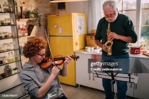 Happy Senior Man And Grandson Having Fun While Playing Saxophone And Violin At Home High-Res Stock Photo