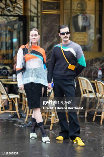 Guest wears rhinestones fringed earrings, an orange / blue / black / gray print pattern wool oversized pullover, a black shiny Varnished leather Cleo...