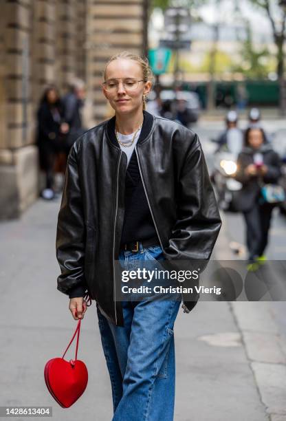 Alexandra Carl wears denim jeans, red heart shaped bag, bomber leather jacket outside Cecilie Bahnsen during Paris Fashion Week - Womenswear...