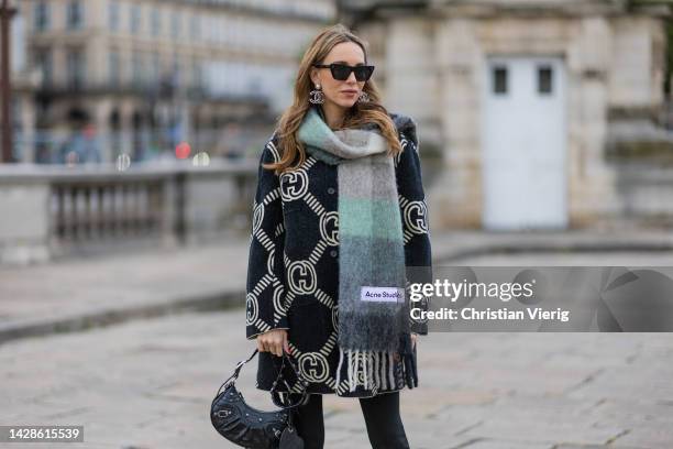 Alexandra Lapp wears Gucci reversible cardigan in black and ecru, Balmain pants, Acne Studios scarf in green and grey, Balenciaga Le Cagole bag in...