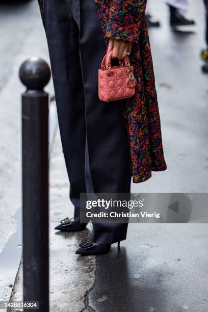 Elisa Taviti wears coat and top with floral print, black high waisted pants, mini Lady Dior bag outside Rochas during Paris Fashion Week - Womenswear...