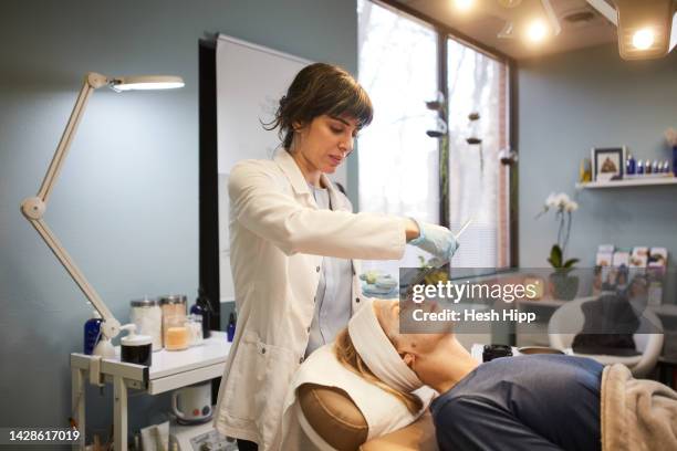 beautician applying mask on patients face - esthéticienne photos et images de collection