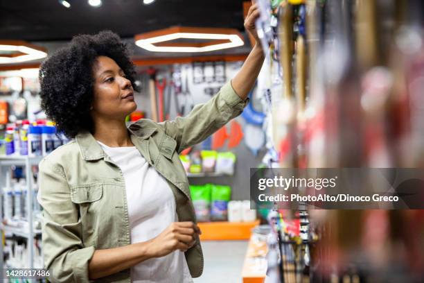 african american female hardware shop owner sorting out products on rack - hardware store fotografías e imágenes de stock