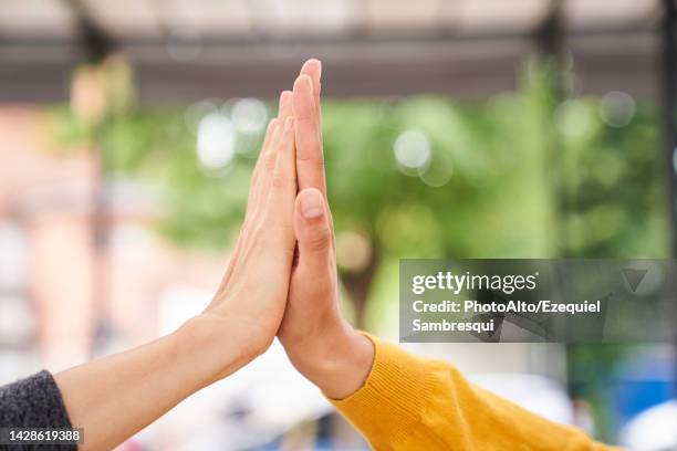 close-up shot of women's hands high-fiving each other - high five stockfoto's en -beelden
