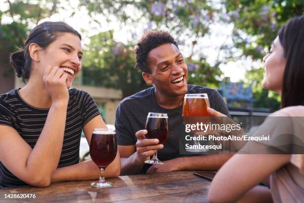 diverse group of happy friends hanging out drinking craft beer at happy hour - craft cocktail stock pictures, royalty-free photos & images