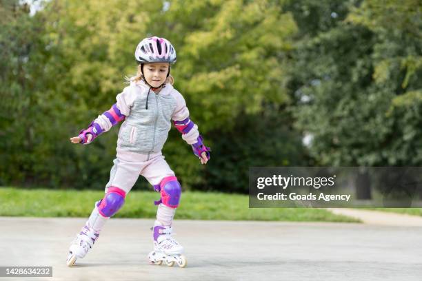 enfant apprenant à faire du patin à roulettes à l’extérieur - coudière photos et images de collection