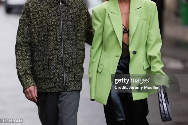 Alice Barbier and Jean-Sebastien Roques seen wearing Loewe shirt, grey pants, Bottega Veneta black boots and green neon suit, black leather pants,...