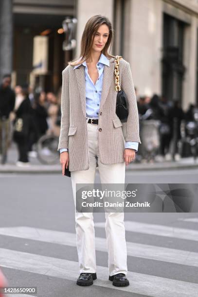 Model is seen wearing a black and white jacket, blue shirt, white pants, black and gold chained bag and black shoes outside the Row show during Paris...