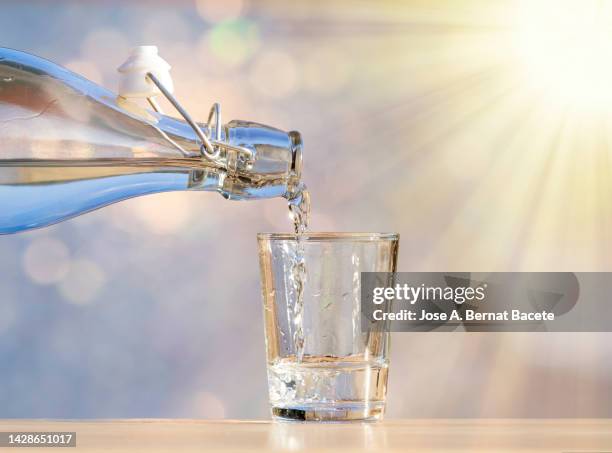 filling a glass of water to drink illuminated by sunlight. - overflowing glass stock-fotos und bilder