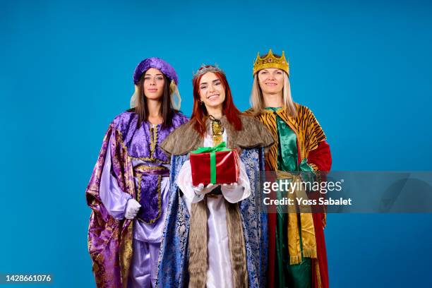 three smiling wise queens handing out a christmas present - 3 wise men stock pictures, royalty-free photos & images