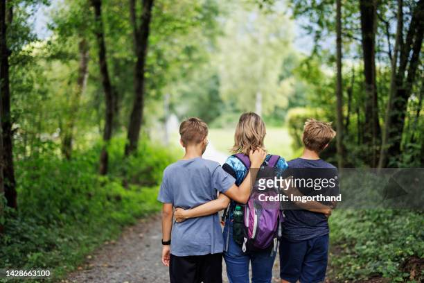 mother and two teenage sons hiking in green forest - single mother teen stock pictures, royalty-free photos & images