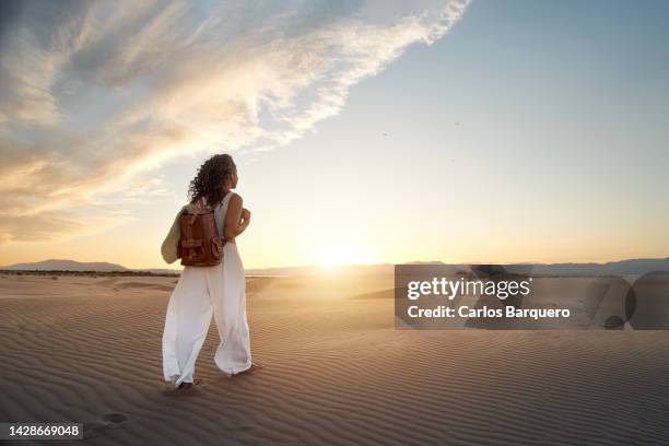 rear view of young black woman walking on sand dune at desert against sky during sunset. - barcelona free stockfoto's en -beelden