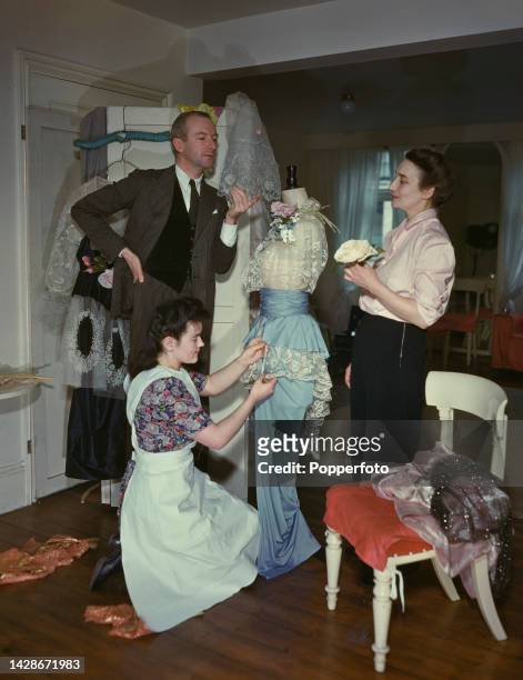 British photographer and designer Cecil Beaton and, on right, costume designer Matilda Etches make final adjustments to one of their costumes for...