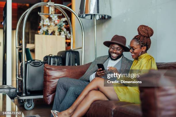 wealthy couple with smartphone in hotel lounge. - luggage trolley stockfoto's en -beelden