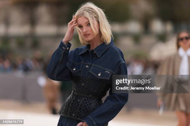 Elsa Hosk is seen wearing a navy blue denim pleated long dress from Dior and a black shiny leather mesh corset from Dior, outside Dior, during Paris...