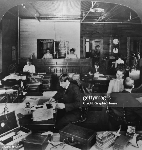 Stereoscopic image showing people working at their desks in the offices of Perfecscopes and Perfec-Stereographs, with the viewers in their cases in...